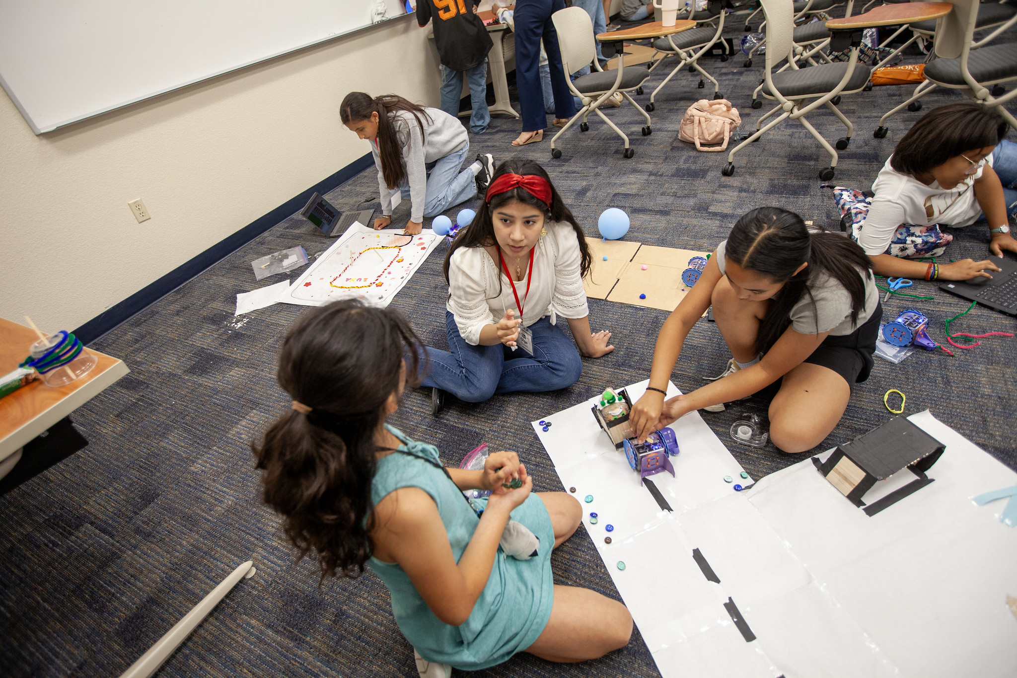 students sitting on the floor programming Linkbot robots