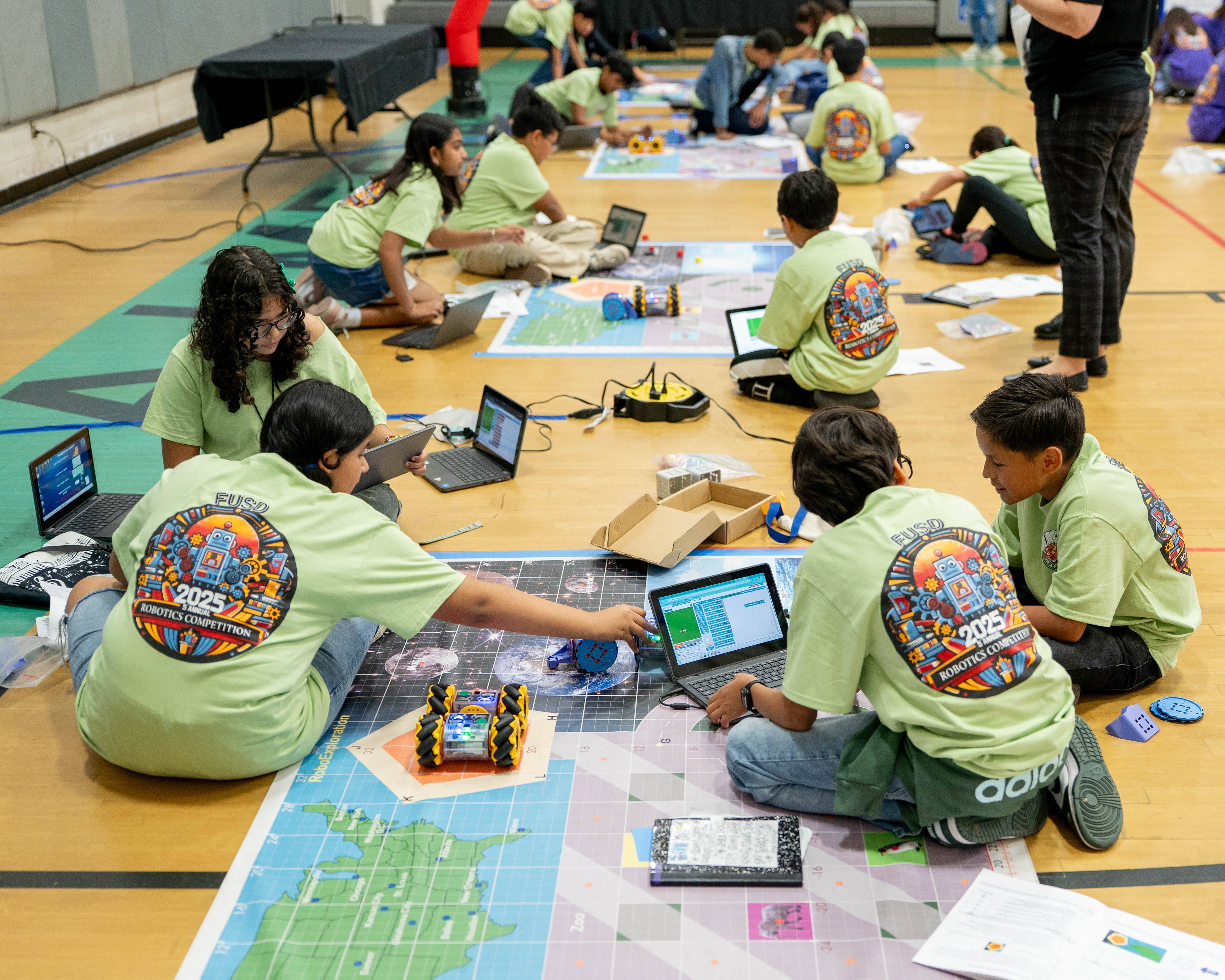 students sitting on the ground, programming Linkbot robots