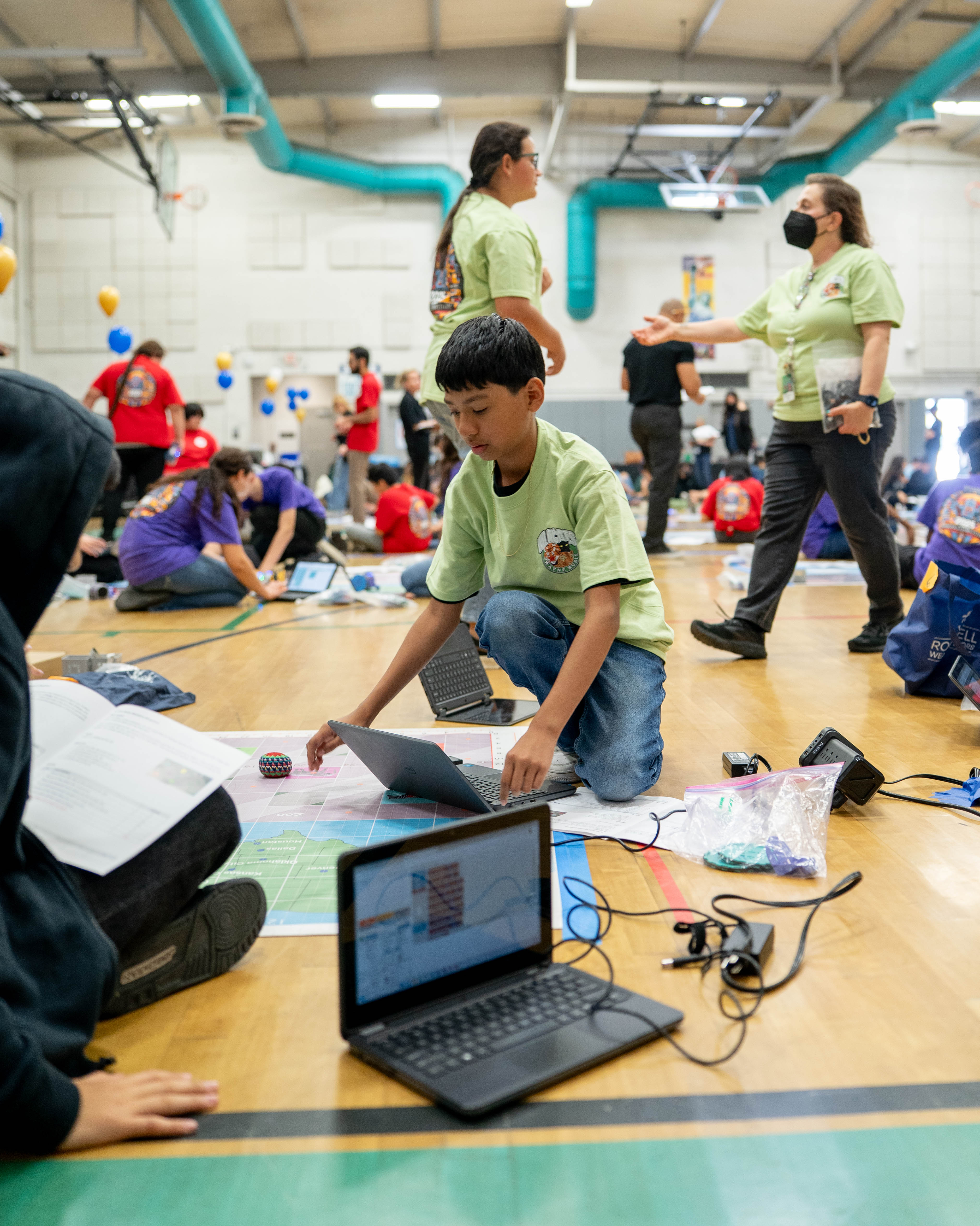 student knelt over RoboPlay mat and laptop