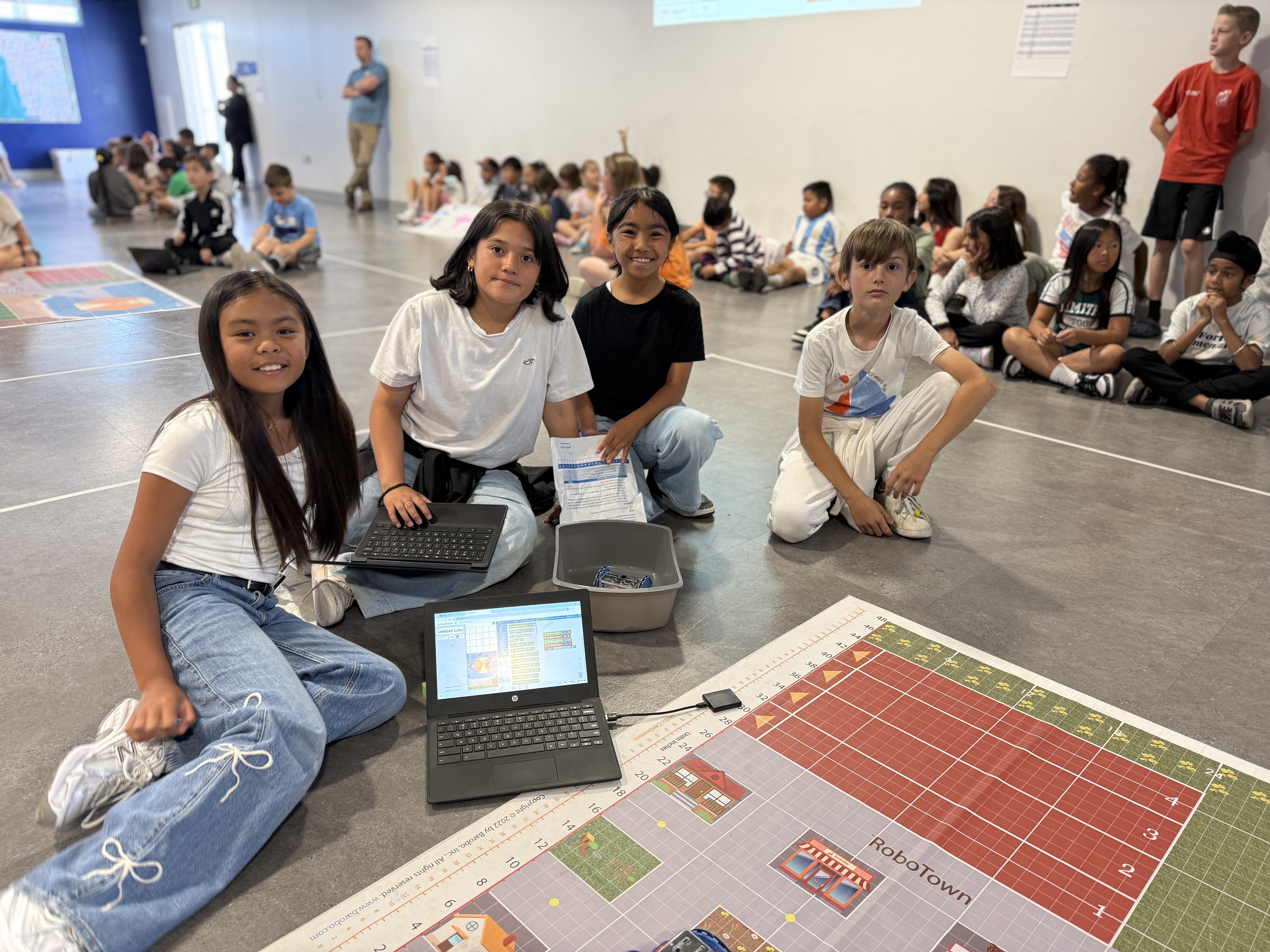 4 students sitting in front of a laptop with code