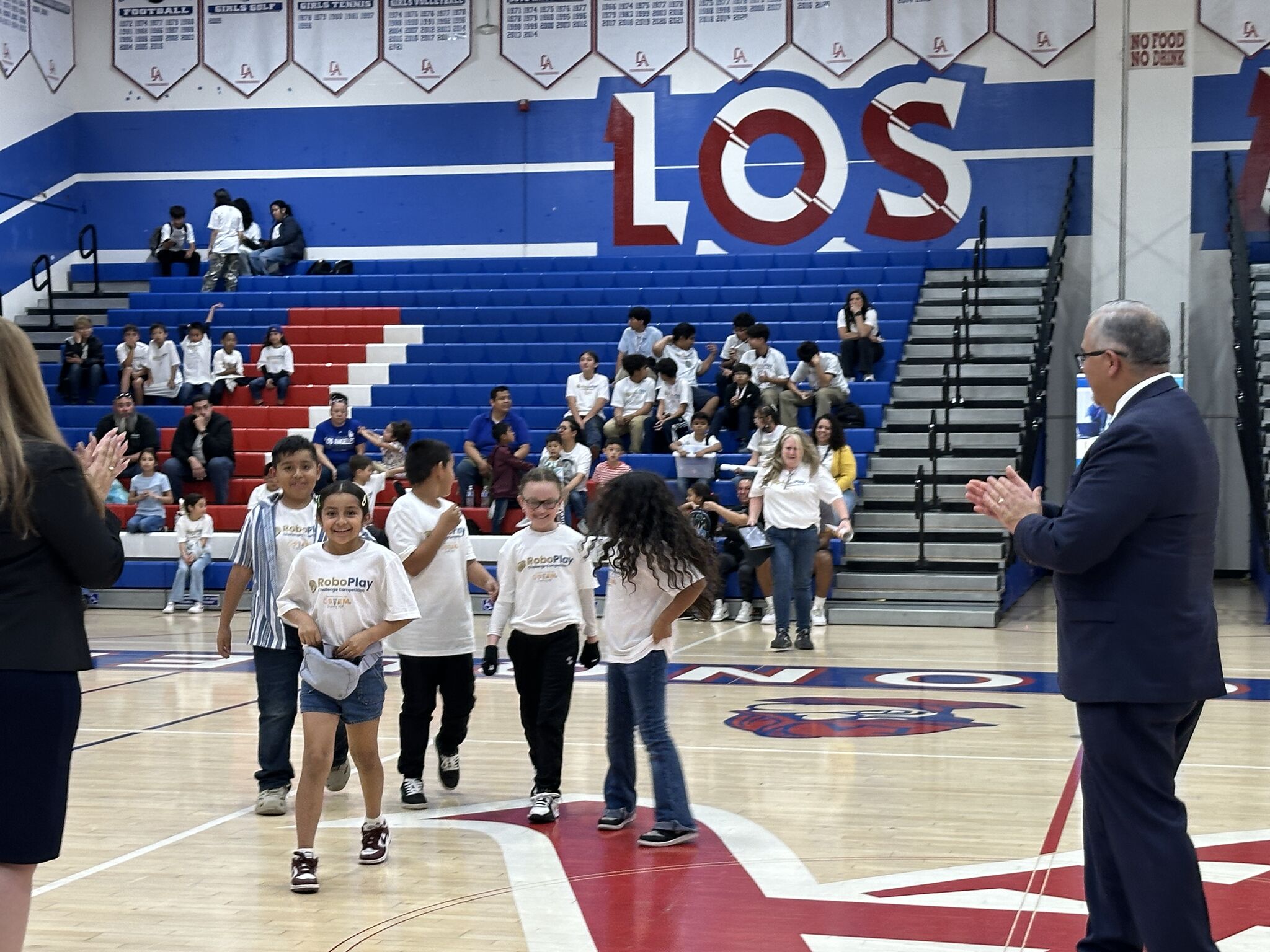 students walking across gym to receive award