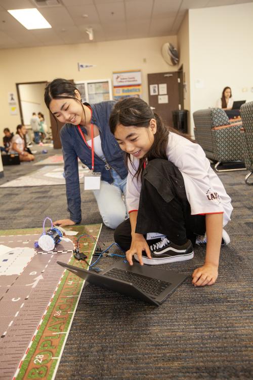 a student and mentor smiling while programming together